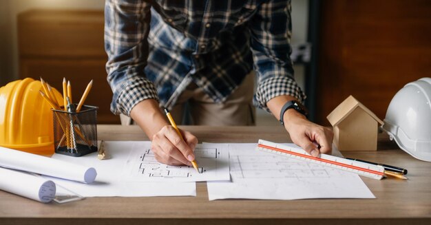 Kollegen diskutieren über Datenarbeit und Tablet-Laptop mit einem Architekturprojekt auf der Baustelle am Schreibtisch in officexA