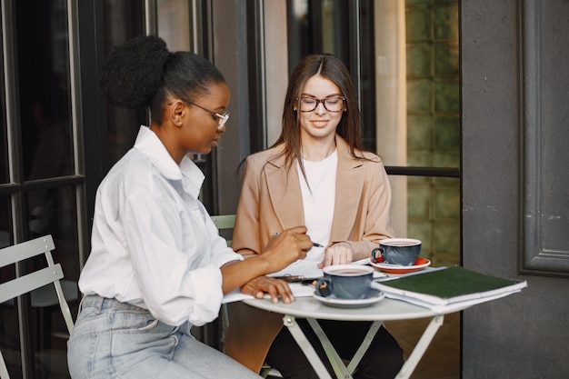 Kolleginnen diskutieren Daten im Café im Freien.