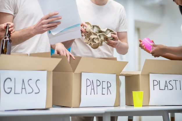 Ökologiebewegung. Junge Leute, die in der Nähe des Tisches stehen und Müll in entsprechende Kisten mit Inschriften sortieren