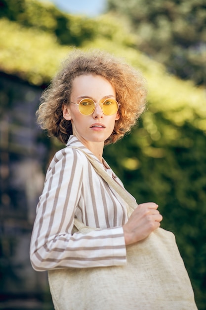 Ökologische Probleme. Junge Frau mit Sonnenbrille auf der Straße mit Öko-Tasche in den Händen