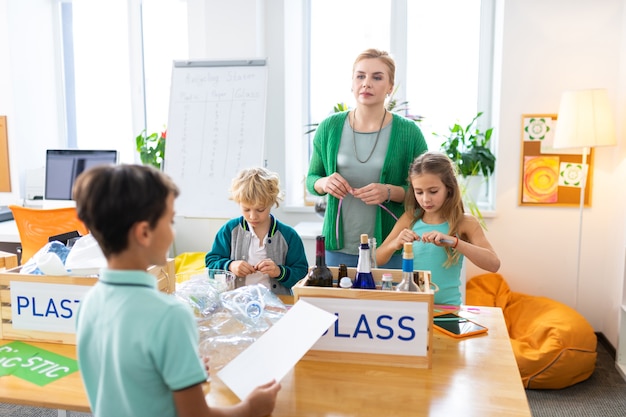 Ökologisches Projekt. Dunkelhaariger Schüler, der seinen Mitschülern und dem Lehrer sein Ökologieprojekt vorstellt