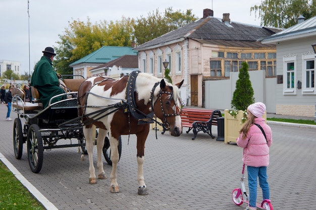 Kolomna Rusia 25 de septiembre de 2021La niña mira el caballo enjaezado al carruaje