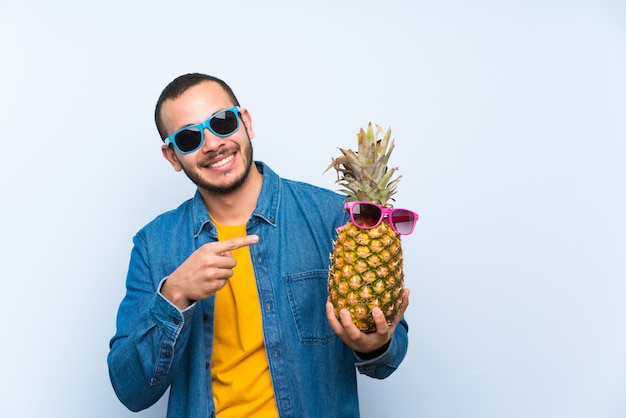 Kolumbianischer Mann, der eine Ananas mit Sonnenbrille hält