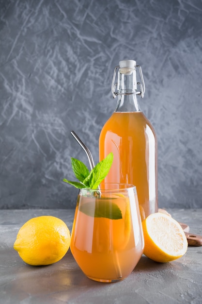 Kombucha gesundes leckeres Getränk in Flasche und Glas mit Zitronengarnitur Minze.