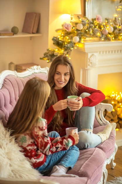 Komfort. Mutter und Tochter sitzen auf dem Sofa und fühlen sich wohl