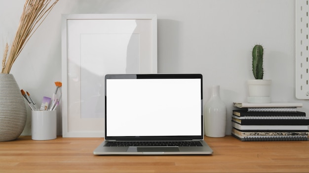 komfortabler Arbeitsplatz mit Laptop-Computer und Büromaterial auf Holztisch und weiße Wand