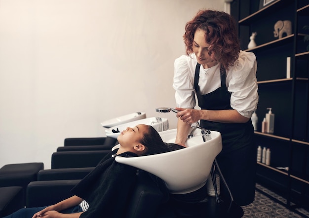 Kommen Sie für die Frisur, bleiben Sie für die Erfahrung Aufnahme eines jungen Mädchens, das sich im Salon die Haare waschen lässt