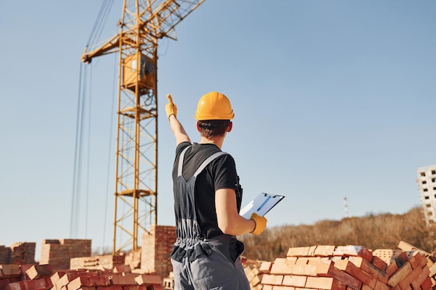 Kommunikation mit dem Kranmann Bauarbeiter in Uniform und Sicherheitsausrüstung haben Arbeit am Bau