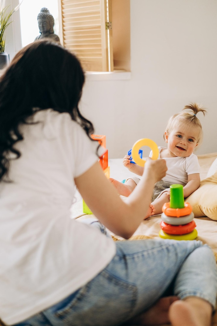 Kommunikation zwischen Mutter und Kind. Mutter spielt zu Hause mit ihrem Baby. Das Kind sammelt eine Spielzeugpyramide. Behandlung des harmonischen Übergangs einer Frau nach der Geburt.