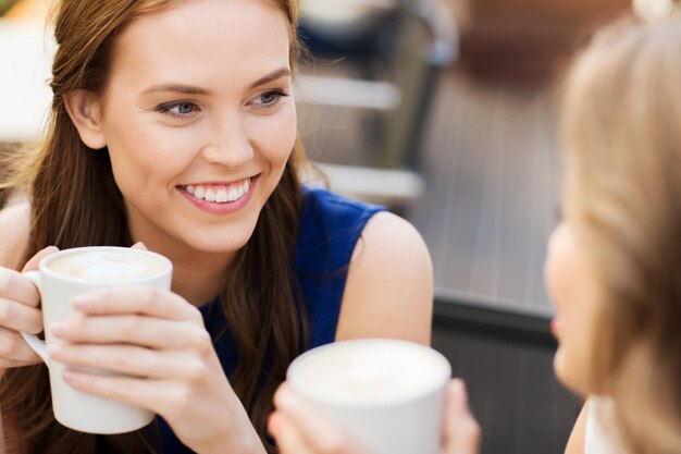 Kommunikations- und Freundschaftskonzept - lächelnde junge Frauen mit Kaffeetassen im Café