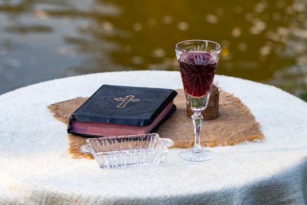 Kommunion nehmen. Tasse Glas mit Rotwein, Brot und Bibel auf Holztischnahaufnahme.