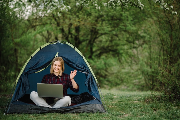 Kommunizieren Sie mit Verwandten, Familie online auf Laptop im Zelt in der Natur