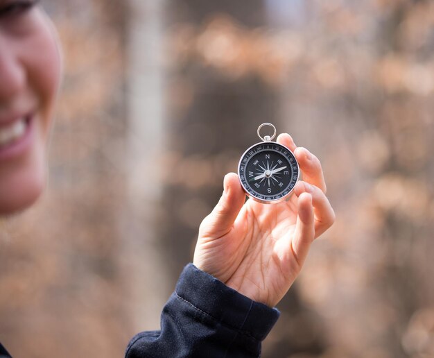 Kompass, der in der Hand eines verschwommenen Gesichts des Abenteuers eines Mädchens im Freien hält