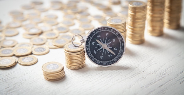 Kompass und Münzen auf dem weißen Schreibtisch