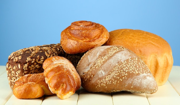 Komposition mit Brot und Brötchen auf Holztisch auf farbigem Hintergrund