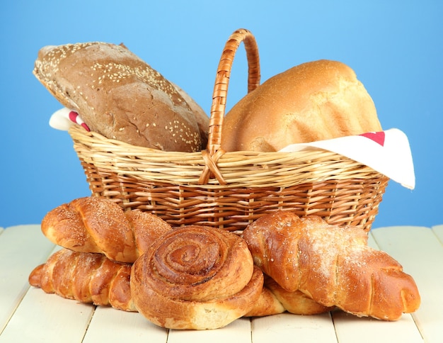 Komposition mit Brot und Brötchen, im Weidenkorb auf Holztisch auf Blau