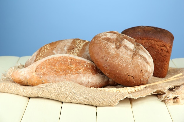 Komposition mit Brot und Sackleinen auf Holztisch auf farbigem Hintergrund