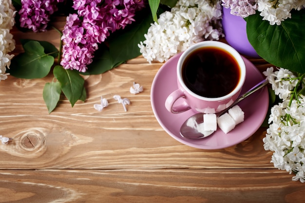 Komposition mit Fliederzweigen und einer Tasse Kaffee auf einem Holztisch