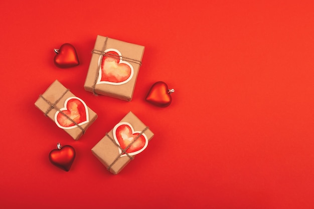 Komposition mit Geschenkboxen und Glasherzen auf Rot. Hintergrund mit Kopienraum für Valentinstag.
