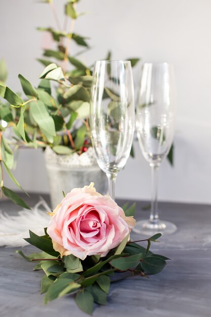 Komposition mit Glas für Champagner. Blumen und Herzen auf grauem Betonhintergrund.