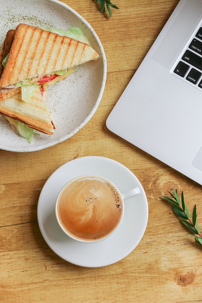 Komposition mit Kaffee, Laptop, Sandwich und Zweig von Pistachi