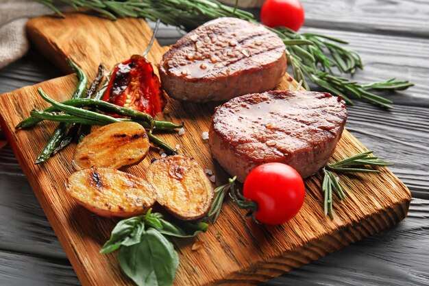 Komposition mit köstlichen Steaks und Gemüse auf einem Holztisch