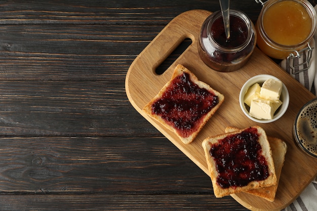 Komposition mit leckeren Toasts mit Marmelade auf Holzbrett, Platz für Text