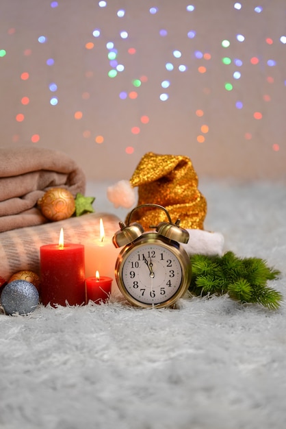 Komposition mit Plaids, Kerzen und Weihnachtsschmuck, auf weißem Teppich auf hellem Hintergrund