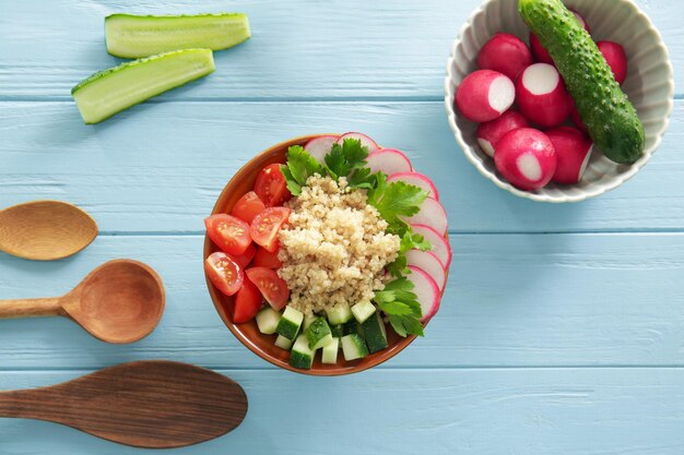 Komposition mit Quinoa-Salat auf farbigem Holzhintergrund