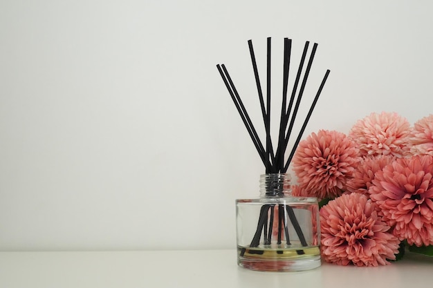 Komposition mit Räucherstäbchen ätherisches Öl in einer Glasvase und rosafarbenen Frottee-Kunstblumen im Inneren eines weißen Raums Weißer Hintergrund Viele Blumen und Duftstäbchen Kopieren Sie Platz