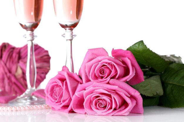 Komposition mit rosa Sekt in Gläsern und rosa Rosen isoliert auf weiß
