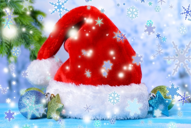 Komposition mit rotem Hut des Weihnachtsmanns und Weihnachtsschmuck auf hellem Hintergrund