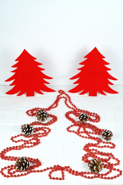 Komposition mit roten Weihnachtsbäumen auf weißem Holztisch