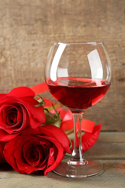 Foto komposition mit rotwein im glas, roten rosen und dekorativem herzen auf holzuntergrund