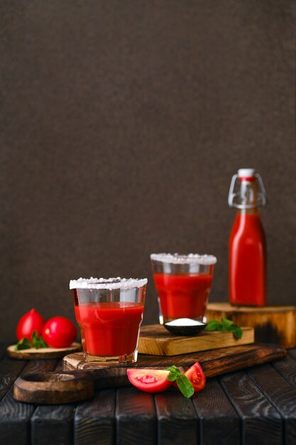 Komposition mit salzigem Tomatensaft auf dunklem Holztisch