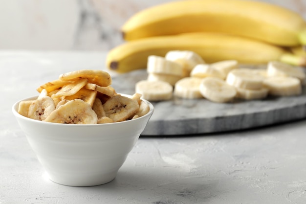 Komposition mit süßen getrockneten Bananenscheiben, frischen Bananen auf Marmorholzhintergrund. Trockenfrüchte als gesunder Snack