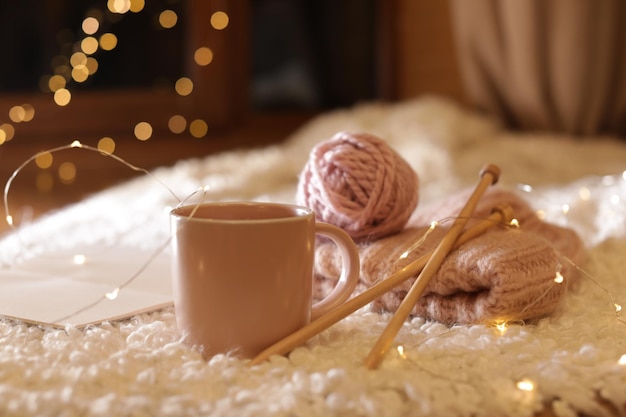 Komposition mit Tasse Heißgetränk Strickgarn und Buch auf Fuzzy-Teppich Winterabend