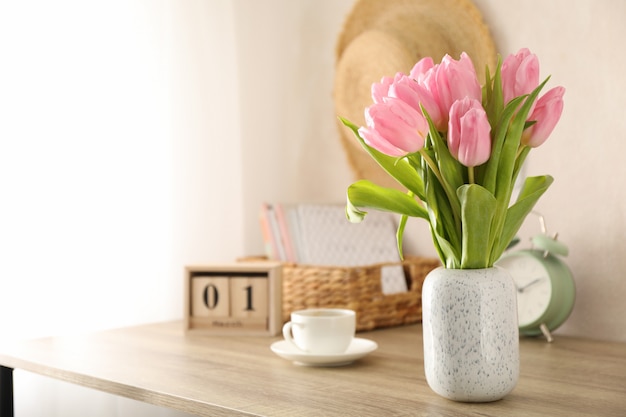 Komposition mit Tulpen in Vase auf hölzernem Hintergrund, Platz für Text