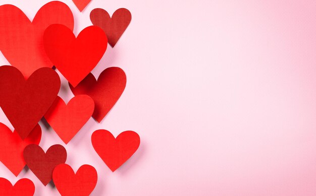 Komposition zum Valentinstag aus volumetrischen roten Herzen auf rosafarbenem Hintergrund