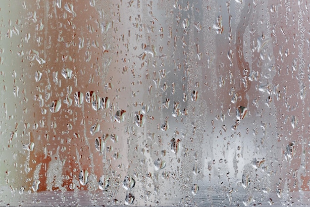 Kondensation am Klarglasfenster, Wassertropfen, Regen. Fensterglas mit hoher Luftfeuchtigkeit. Hintergrund der natürlichen Wasserkondensation