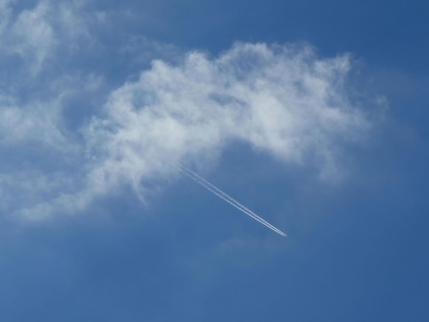 Kondensstreifen des Rauchs vom Düsentriebwerk des Flugzeugs über dem blauen Himmel aus der Wolke