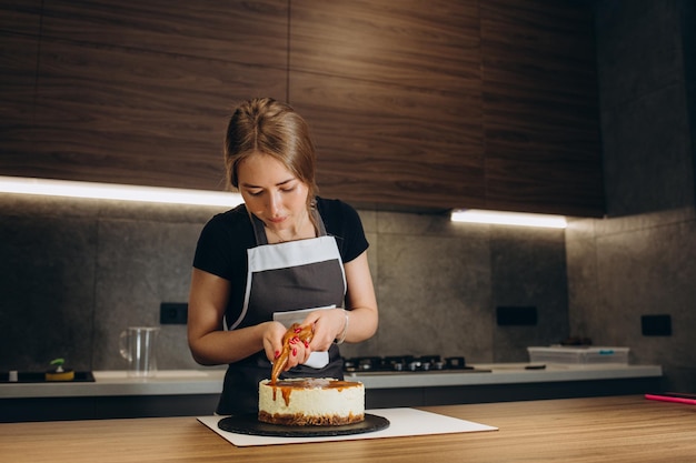 Konditor bei der Arbeit Sahnetorte dekorieren Kochtisch bereitet einen Kuchen auf grauem Hintergrund zu