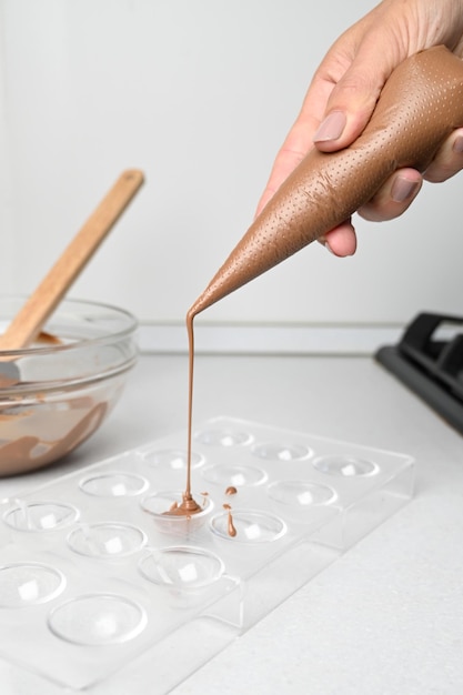 Konditor, der heiße Schokolade zu Schokoladenformen temperiert Desserts kochen