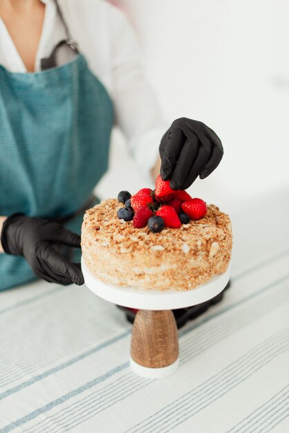 Konditor, der Honigkuchen vorbereitet, der mit Beeren-Nahaufnahme-Süßspeisen verziert wird