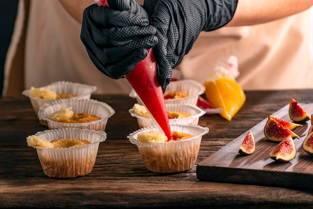 Konditor füllt Muffins mit Marmelade Prozess der Herstellung von Cupcakes von Hand Frau kocht Gebäck