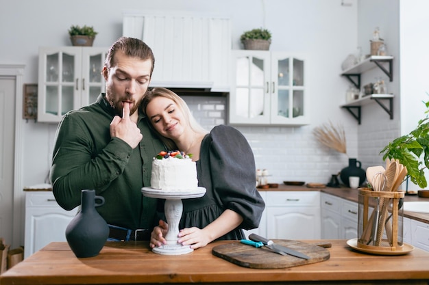 Konditor Konditor junge kaukasische Frau mit Ehemann Freund Mann versuchen Geschmack von Kuchen auf Küchentisch Kuchen Cupcakes und süßes Dessert