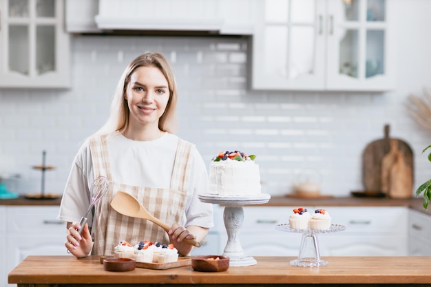 Konditor Konditor junge kaukasische Frau mit Kuchen auf Küchentisch