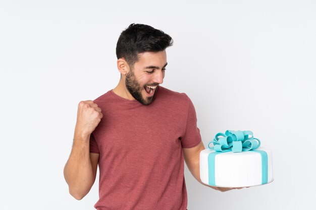 Konditor mit einem großen Kuchen lokalisiert auf weißer Wand, die einen Sieg feiert