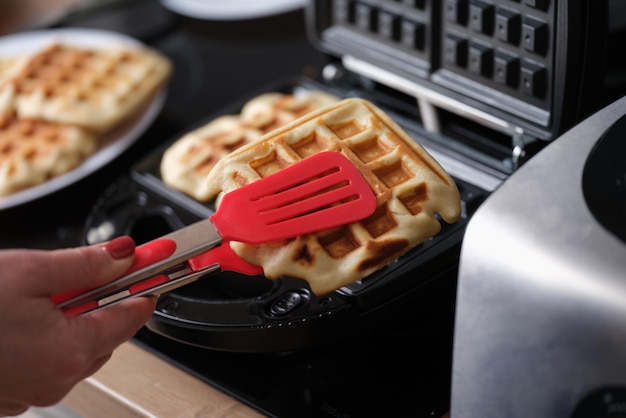 Konditor nimmt heiße Waffeln aus dem Waffeleisen in der Küche