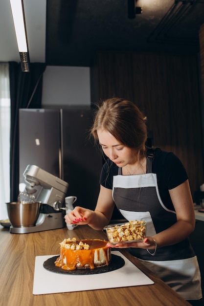 Konditorin in einer Küche Frau in Uniform Professionelle verziert den Kuchen